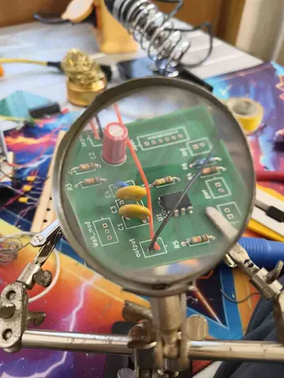 The same circuit board manufactured and hand-soldered, viewed through a magnifying glass